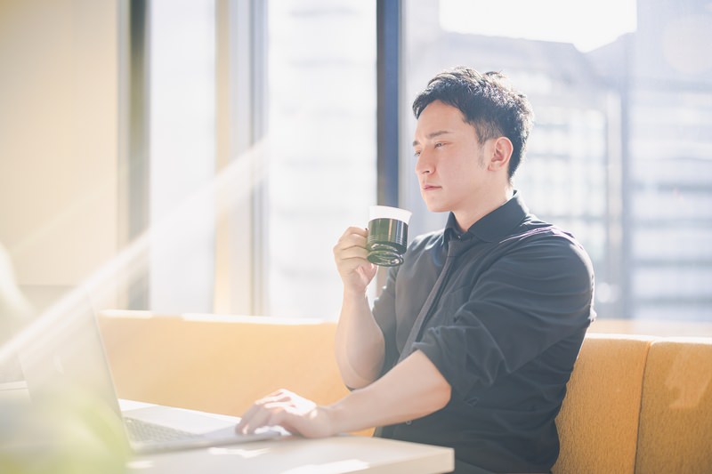 コーヒーを飲みながら働く男性